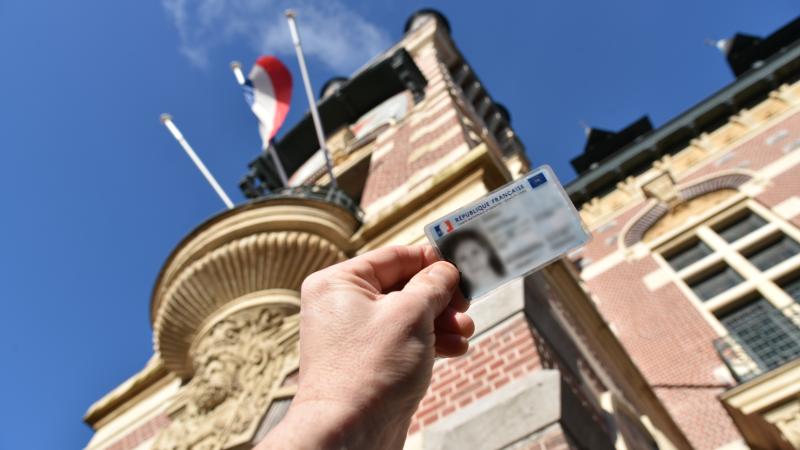 Photo d'une carte d'identité devant le Beffroi de l'Hôtel de Ville. 