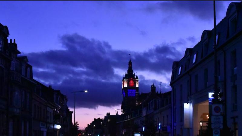 Photo du beffroi de nuit, éclairé en bleu, blanc et rouge.